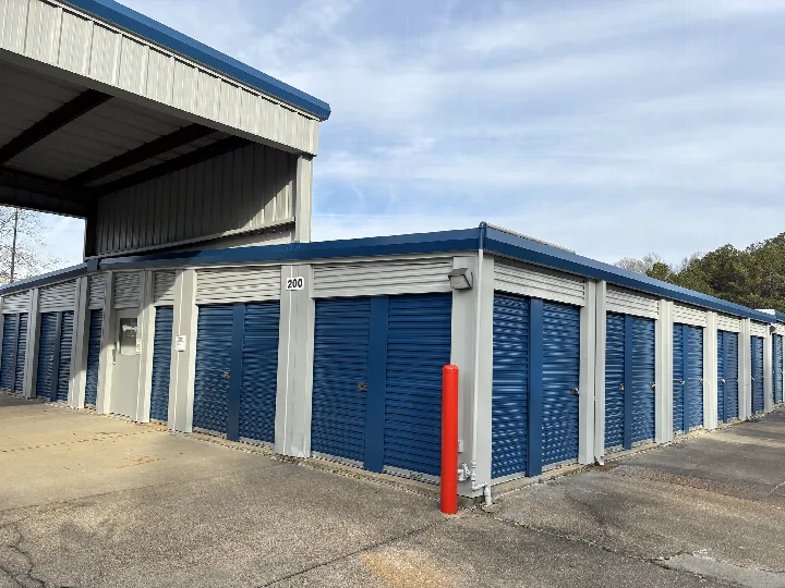 Self-storage building with gray walls, blue doors, and blue roof trim