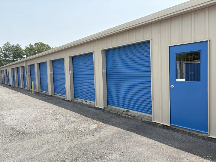 Beige self-storage building with blue roll-up doors and blue entry door